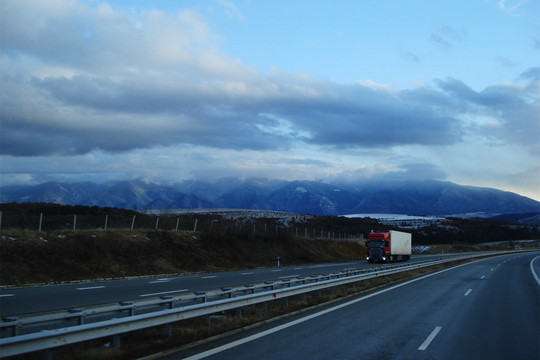 Tolle Wolken und Berge im Hintergrund waehrend der Fahrt mit dem LKW auf der Autobahn.