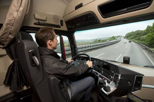 LKW-Fahrer im Fahrerhaus auf der Autobahn mit Tempomat unterwegs.