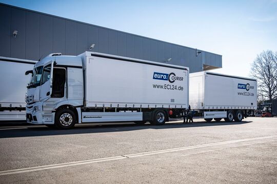 18t LKW mit Anhänger und Branding im Sonnenschein auf Firmenhof.