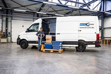 Transporter in Umschlagshalle mit Ware auf Palette.