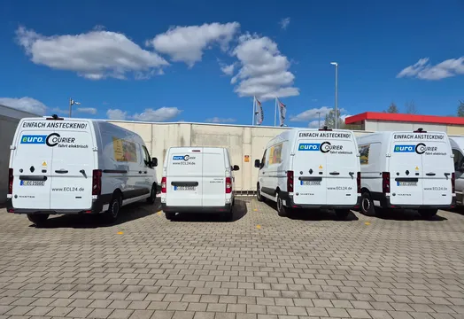 4 Elektrotransprter stehen am Ladepunkt auf dem Firmengelände von euo.COURIER