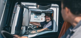 Two people in their respective own truck look at each other through the window