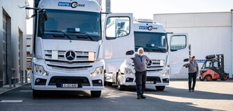 Employees stand in front of their trucks with opened doors