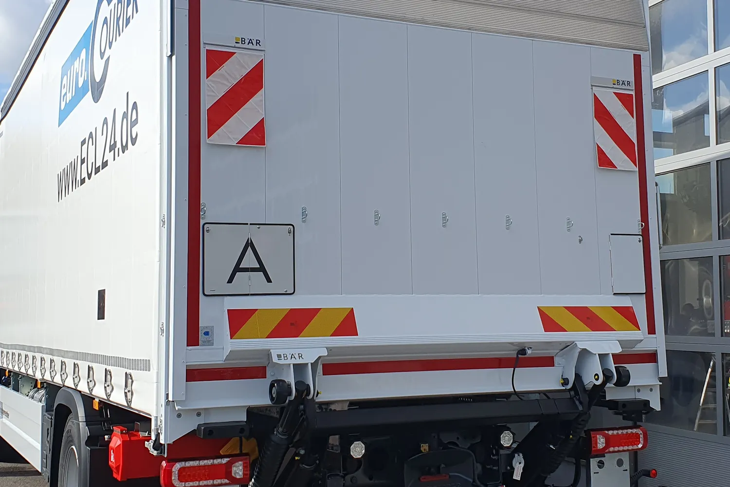 LKW mit aufgeklappter Warntafel für Abfalltransporte.